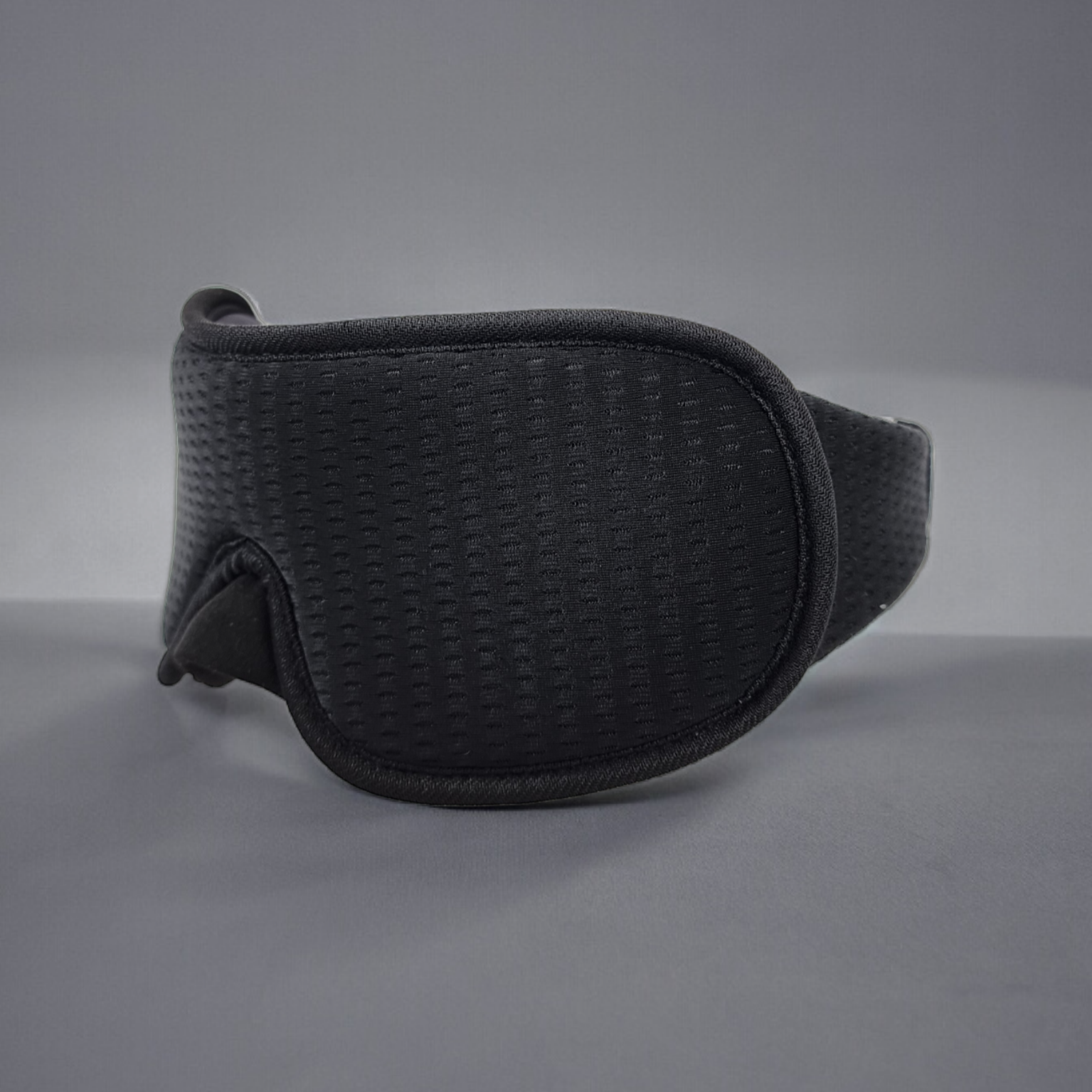 Black 3D sleep mask on a grey background